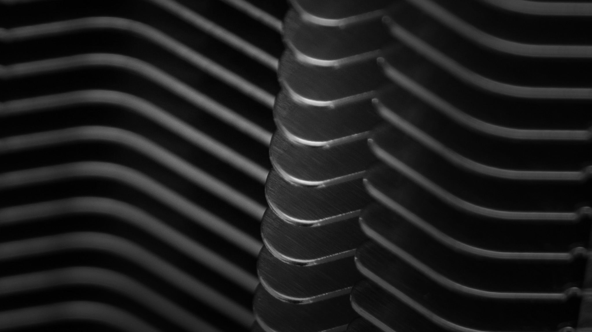 parallel metal cooling fins with a repeating ribbed pattern and dramatic highlights against a dark background.